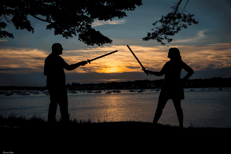 Whitney and Ryan swordfight, in silhouette against the setting sun